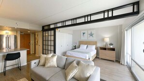 A modern bedroom with a bed, bedside table, and a view of the living area.