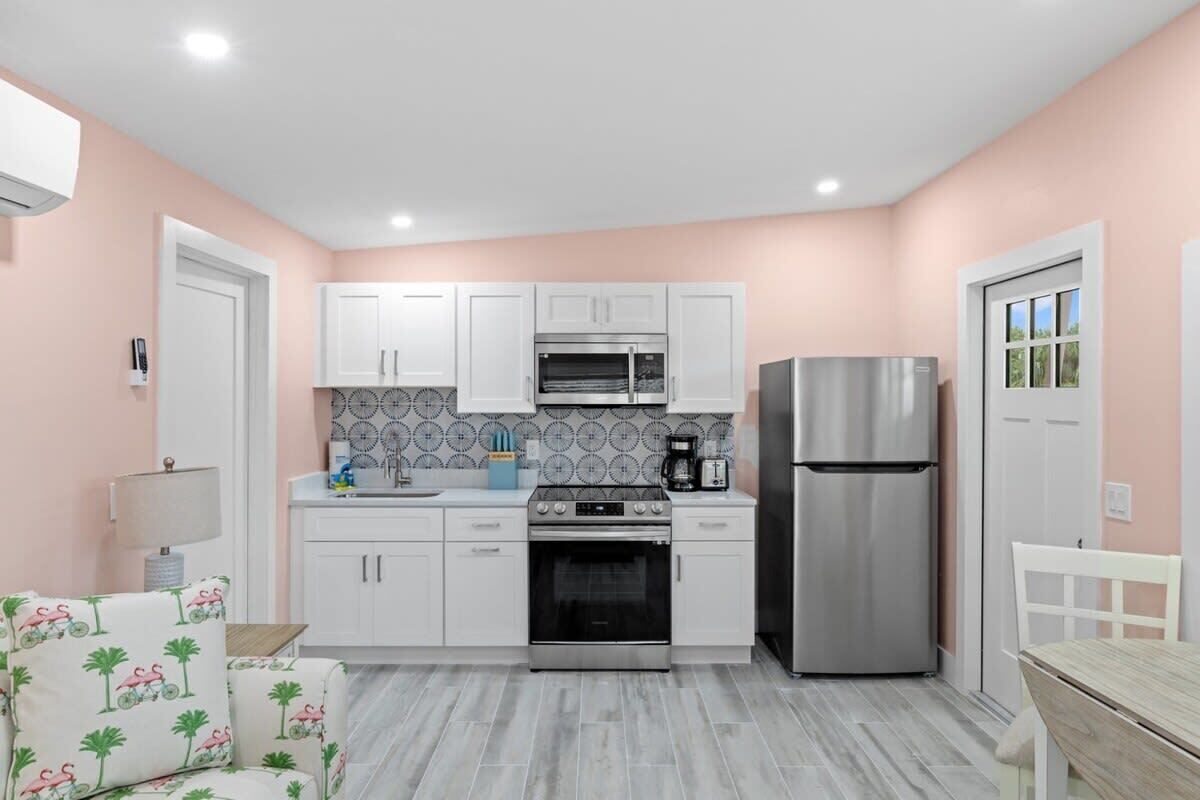 A compact kitchen with white cabinets, a stainless steel oven, and a refrigerator.