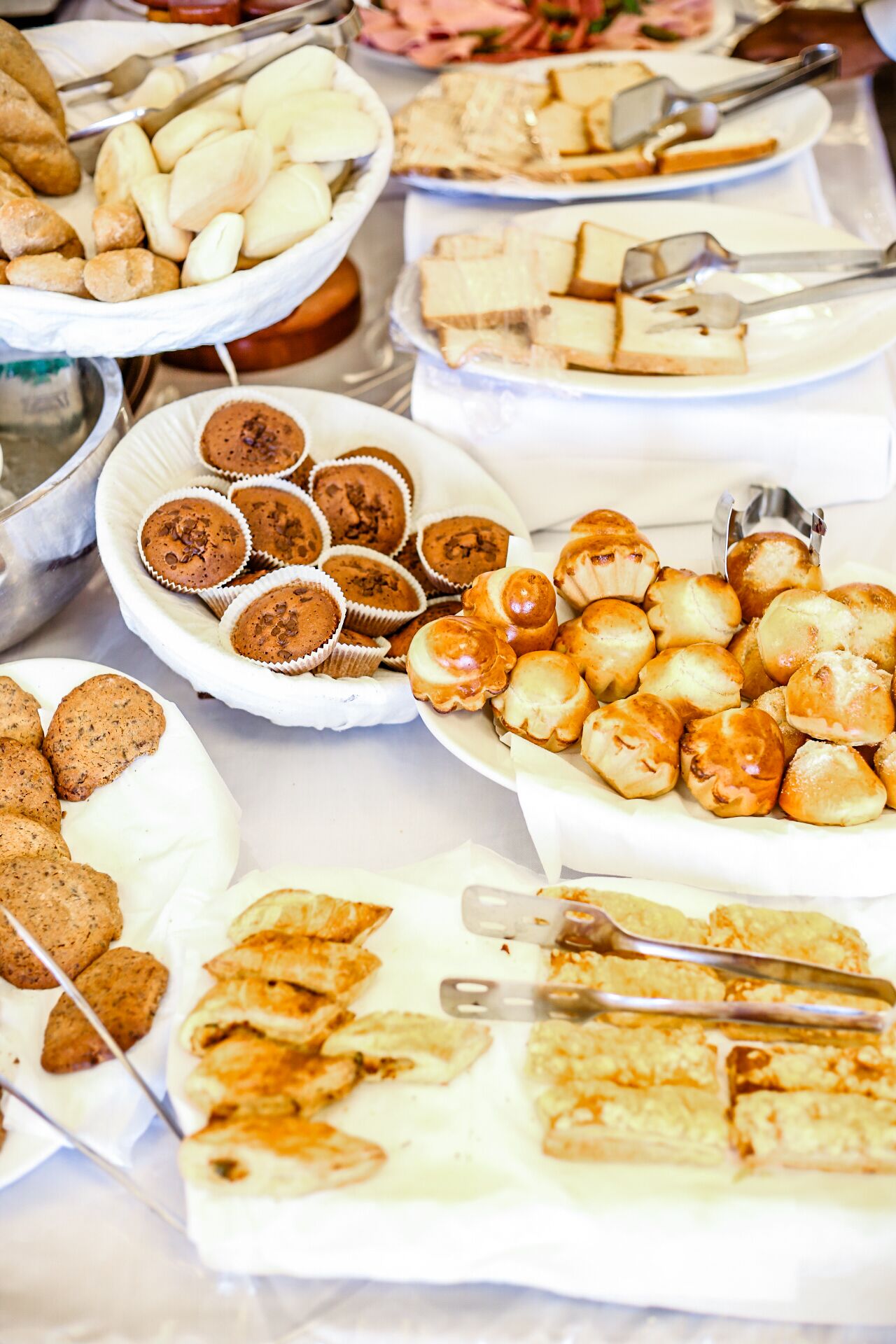A buffet with various food items including muffins, pastries, and sandwiches.