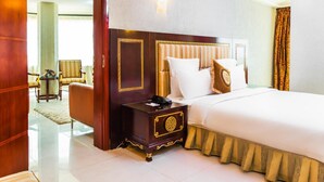 Quarto de hotel com uma cama grande, uma mesa de cabeceira, uma cadeira e um sofá.