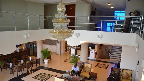 Um hall amplo com um lustre imponente, diversas áreas de estar e uma recepção à vista.