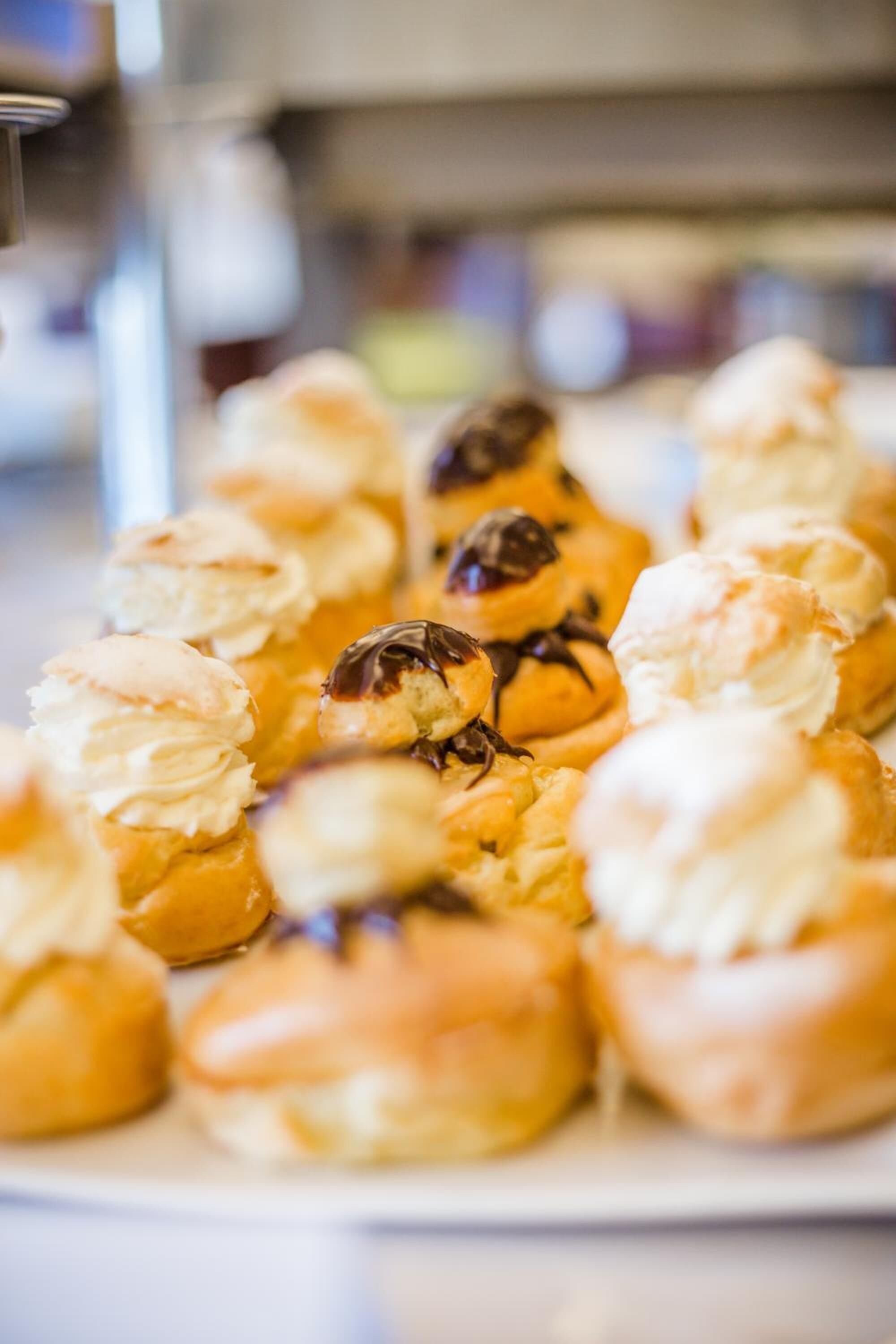 Un plateau de viennoiseries, probablement des croissants, dont certains sont recouverts de chocolat et d’autres de crème.