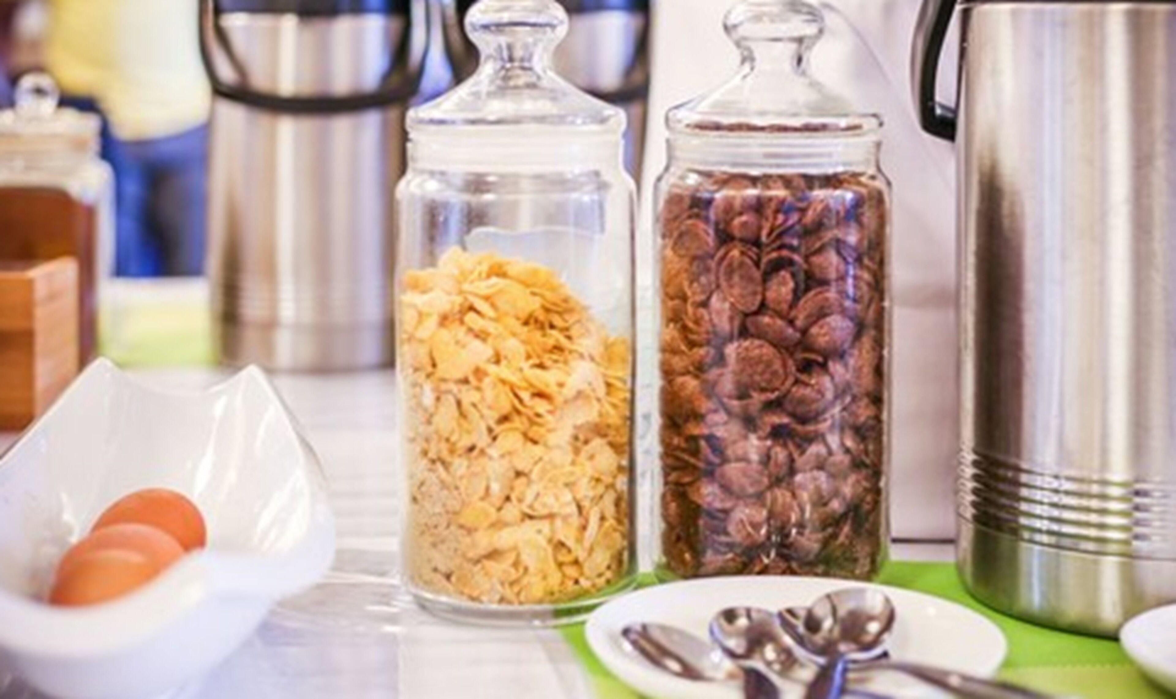Dos frascos de vidrio llenos de granola y nueces sobre una encimera de cocina.