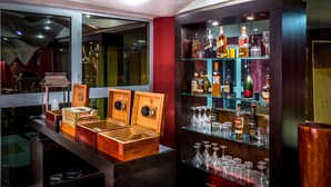 Uma área de bar com vitrines de madeira e prateleiras cheias de garrafas de bebidas e copos.