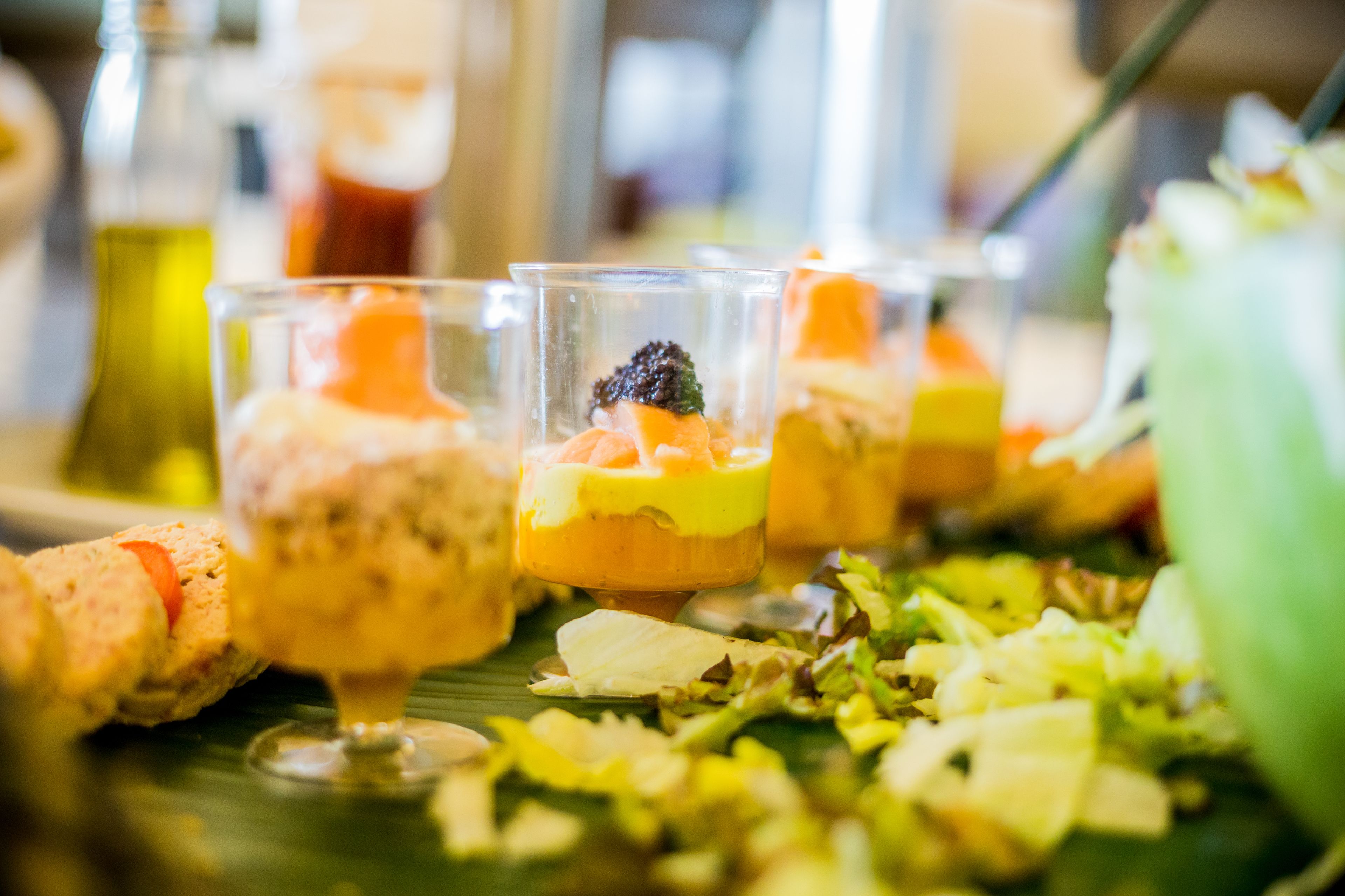 Une table sur laquelle se trouvent divers aliments, notamment un saladier vert et un verre contenant un dessert.