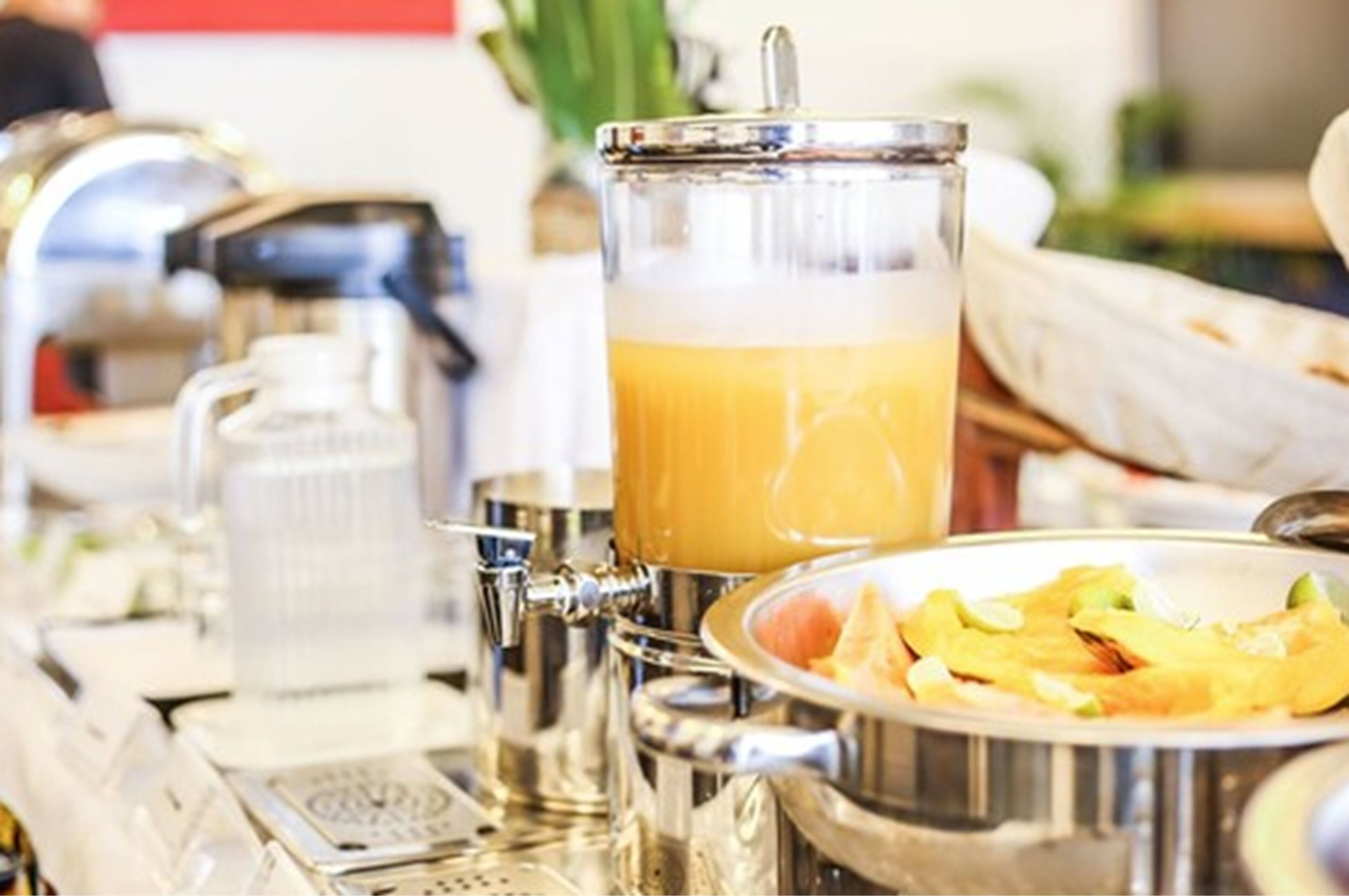 A breakfast setup with a coffee machine, a glass carafe, and a plate of food.