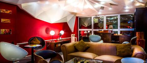 Una sala de estar moderna con una pared de acento roja, una mesa de centro de vidrio y muebles contemporáneos.