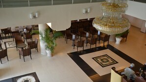 Um hall amplo com várias áreas de estar, um lustre grande e um padrão decorativo no chão.