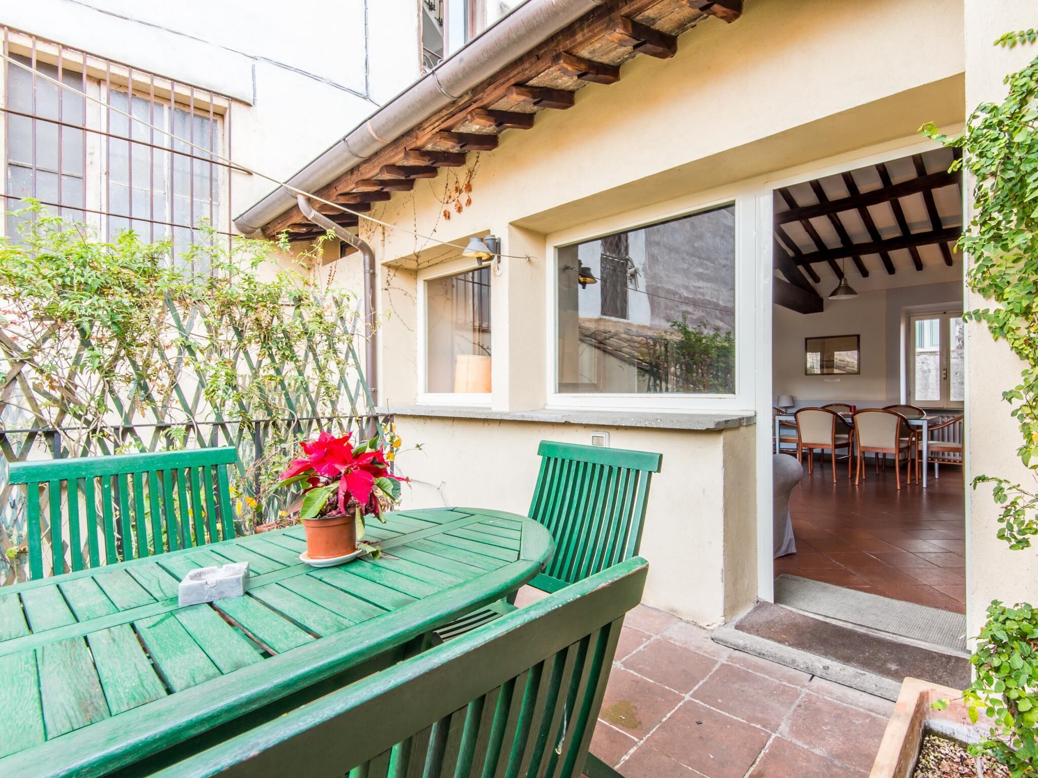 A green wooden table and chairs in a patio area with a potted plant.