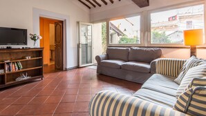 A living room with a sofa, a television, and a bookshelf. - RSH Campo de Fiori Luxury House (Rome)