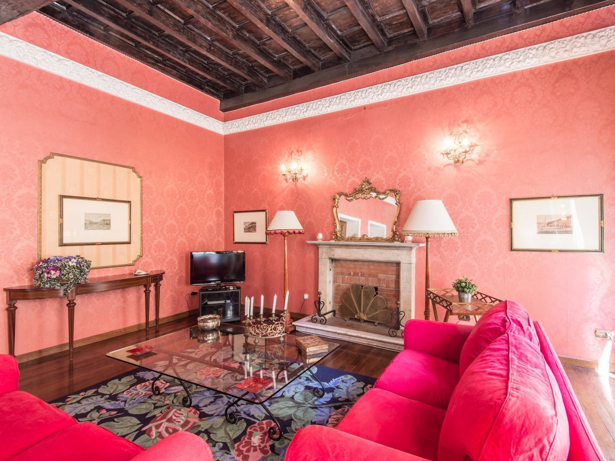 Un salon avec une cheminée, un téléviseur et des meubles rouges.