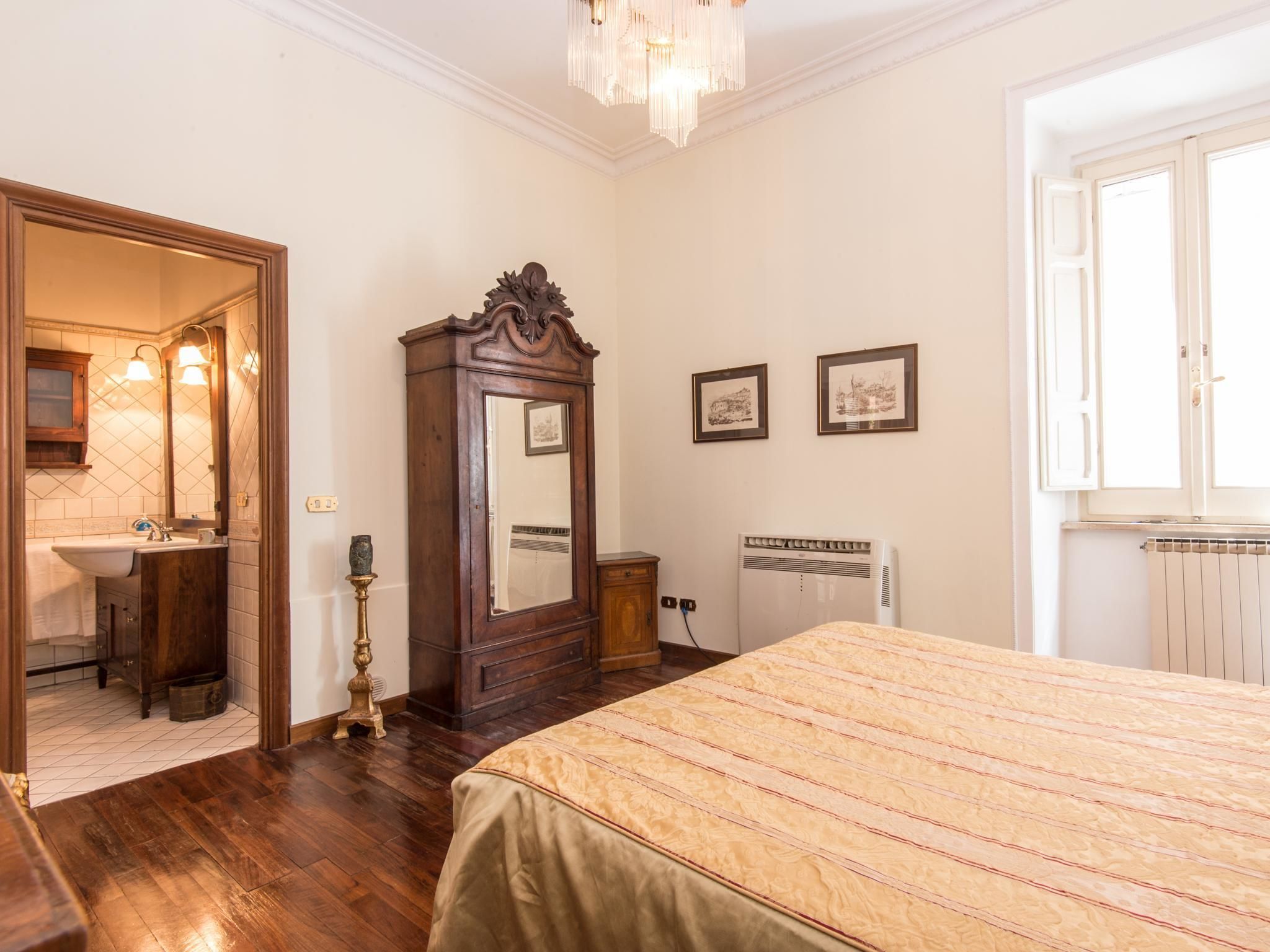 A bedroom with a wooden bed, a dresser, a mirror, a radiator, and a window.