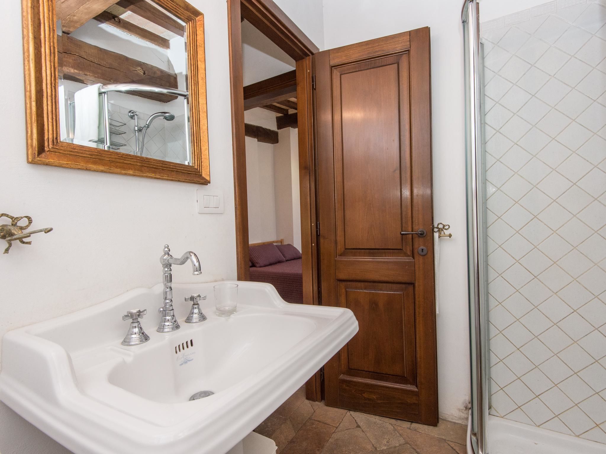 A bathroom with a white sink, a wooden door, and a shower area.