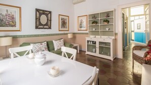 A dining area with a white table and chairs, a cabinet with glass doors, and a hallway leading to another room. - RSH Ara Pacis Terrace Apartment (Rome)