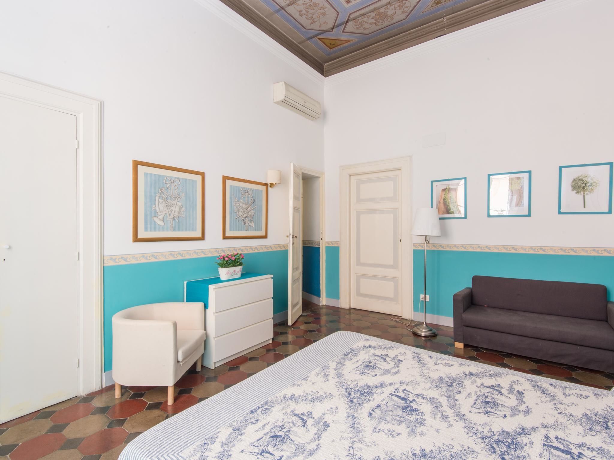 Una habitación con una paleta de colores blanco y azul, que incluye un aparador blanco, un sofá marrón y una alfombra estampada.