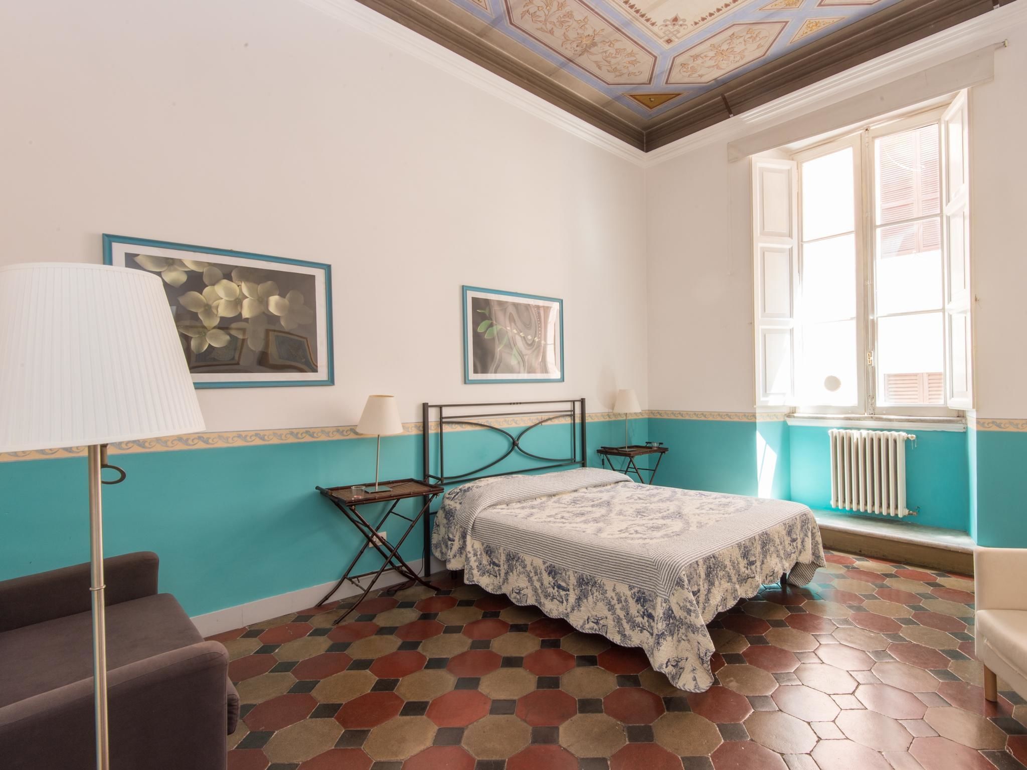 Een kamer met een bed, een lamp en een raam.