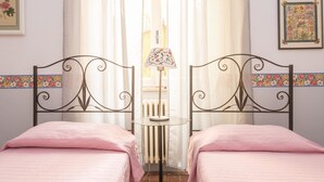 A room with two beds, a small table with a lamp, and curtains. - RSH Ara Pacis Terrace Apartment (Rome)