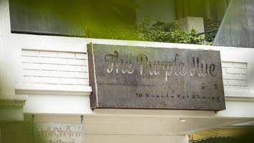 Schild mit der Aufschrift 'The Purple House', der Zahl '56' und 'Nghien Tri Phuc' darunter.