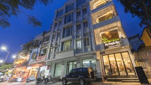Um edifício de vários andares com uma cafeteria no térreo e varandas no andar superior adornadas com plantas.