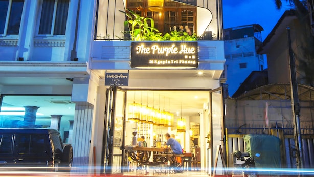 Um edifício de vários andares com um restaurante chamado "The Purple Hue" no andar térreo.