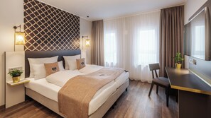 A modern hotel room with a large bed, a desk, and a TV.
