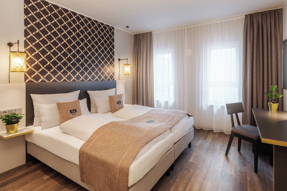 A modern hotel room with a large bed, a desk, and a TV.