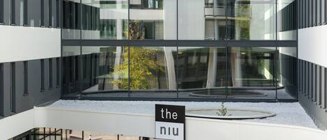 Un edificio moderno con varios pisos, grandes ventanas de vidrio y un letrero que dice "the niu".