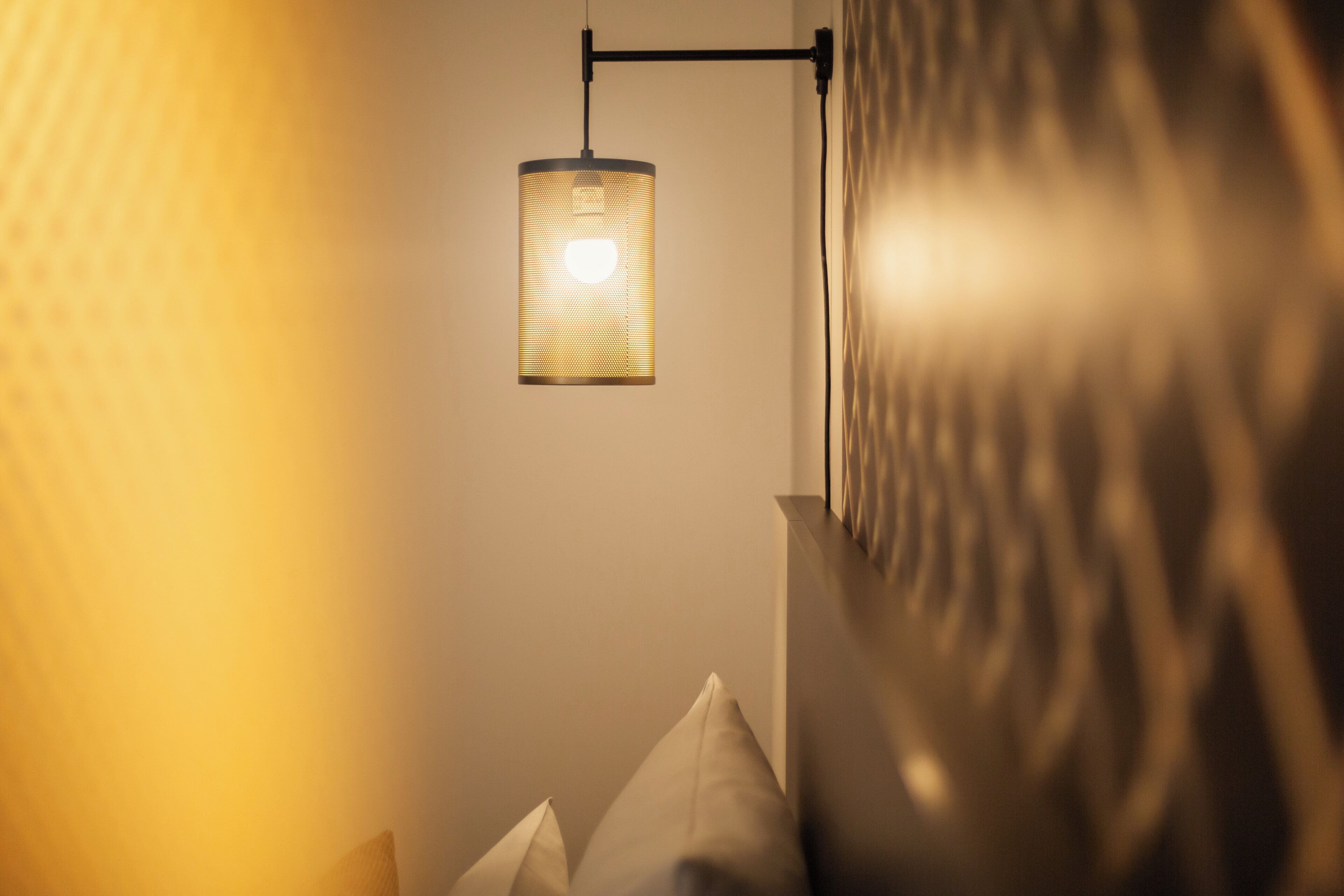 A corner of a room with a hanging light fixture and a textured wall.