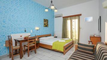 Um quarto com cama, escrivaninha com cadeiras, sofá, janela com cortinas e um quadro na parede.