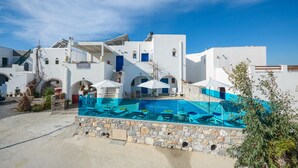A white building with a pool and blue umbrellas. - Studios Sofia (Naxos)