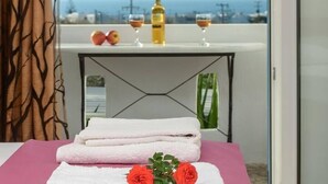 A room with a bed, a table with towels and a bottle, and a view of the sea. - Studios Sofia (Naxos)
