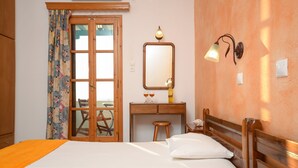 A hotel room with a bed, a wooden desk, a mirror, and a lamp. - Studios Sofia (Naxos)