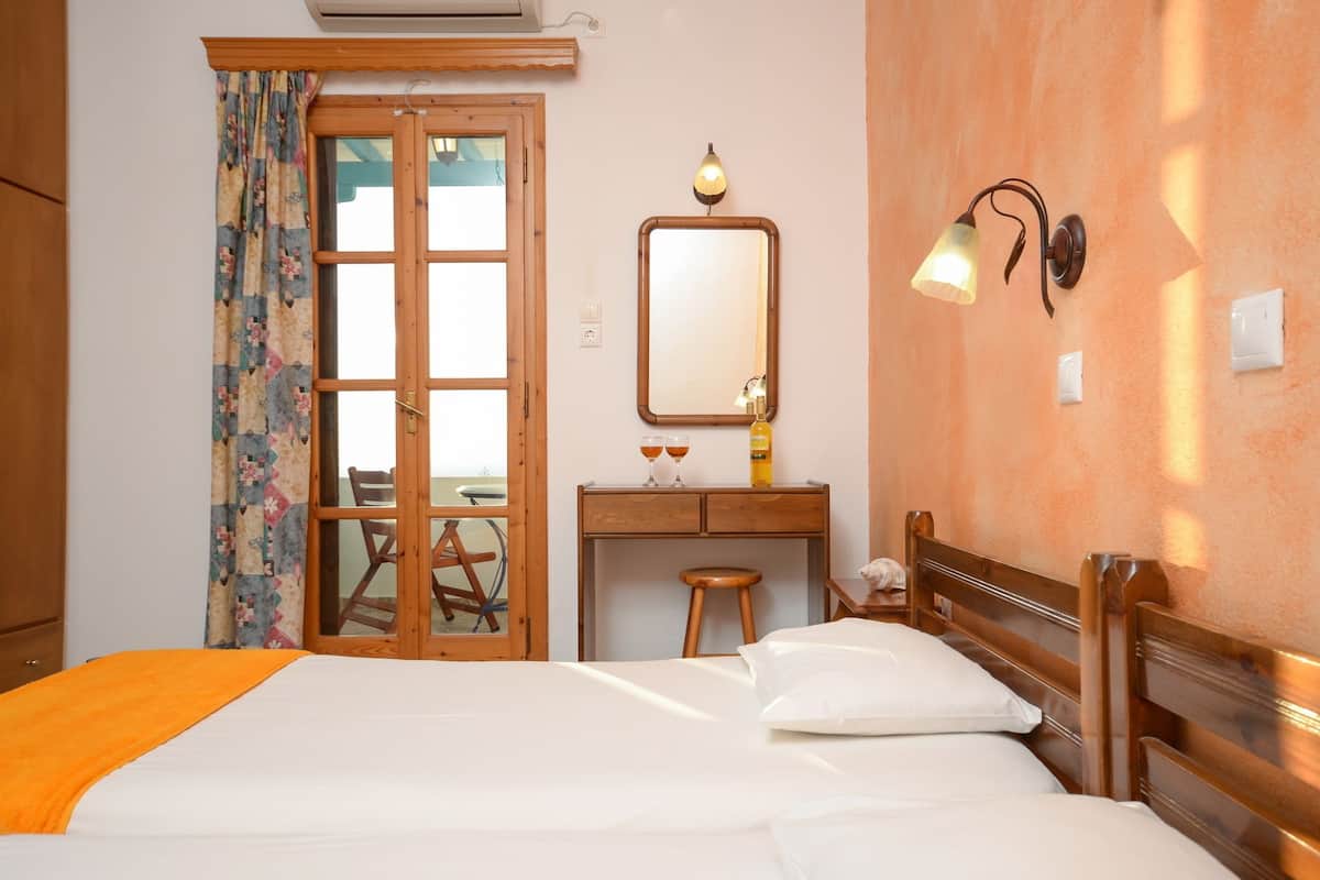 Quarto de hotel com cama, escrivaninha de madeira, espelho e luminária.