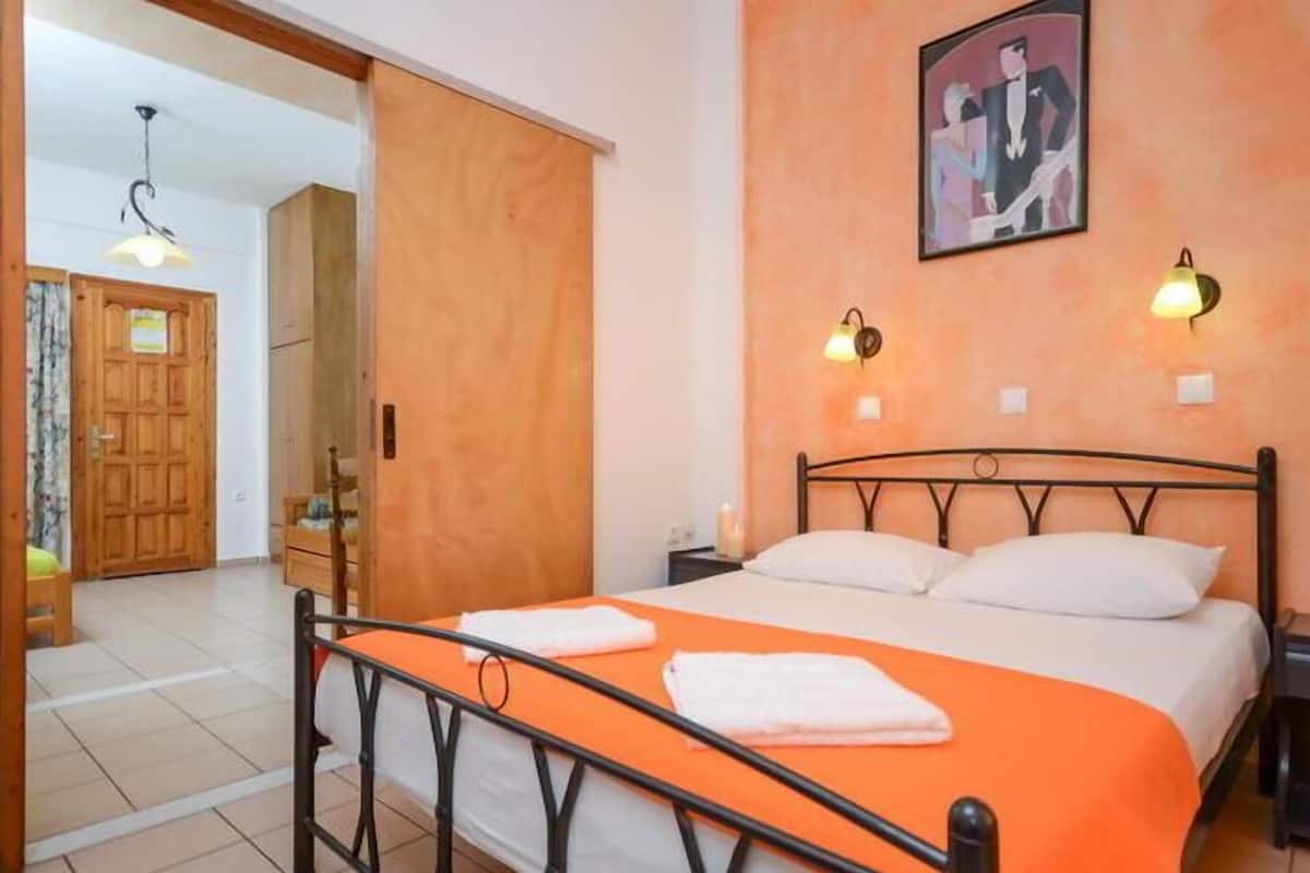 Quarto com cama, porta de madeira e um quadro na parede.