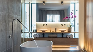 A modern bathroom with a large bathtub, a glass shower enclosure, and a wooden vanity with a sink and decorative items.