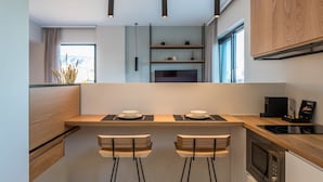 A modern kitchen with a central island, bar stools, a microwave, and a coffee machine.