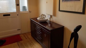 Une pièce comprenant un meuble en bois, un récipient posé sur le dessus, un porte-manteau et une œuvre d’art encadrée accrochée au mur.