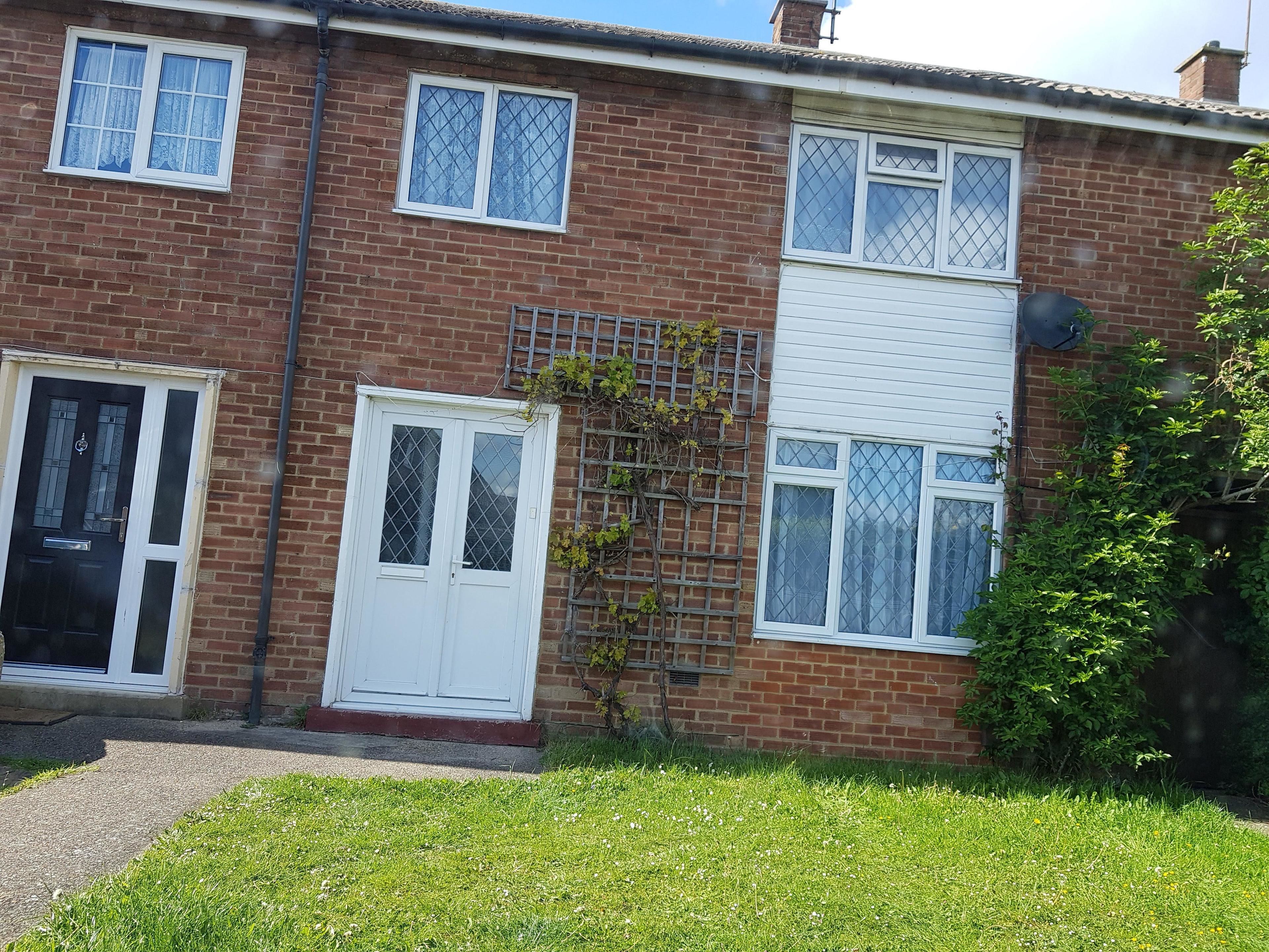 A two-story brick house with a front door, a small garden, and a satellite dish.