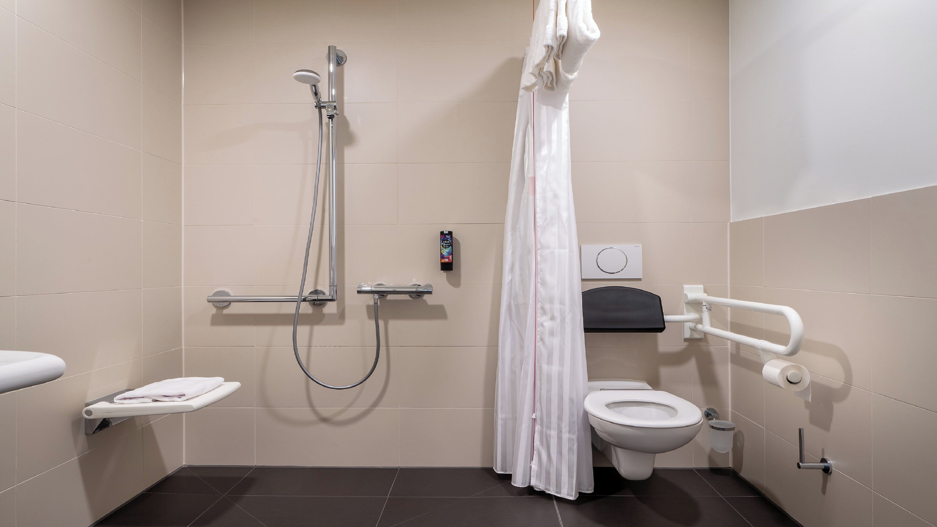 Ein modernes Badezimmer mit Dusche, Toilette und Handtrockner.