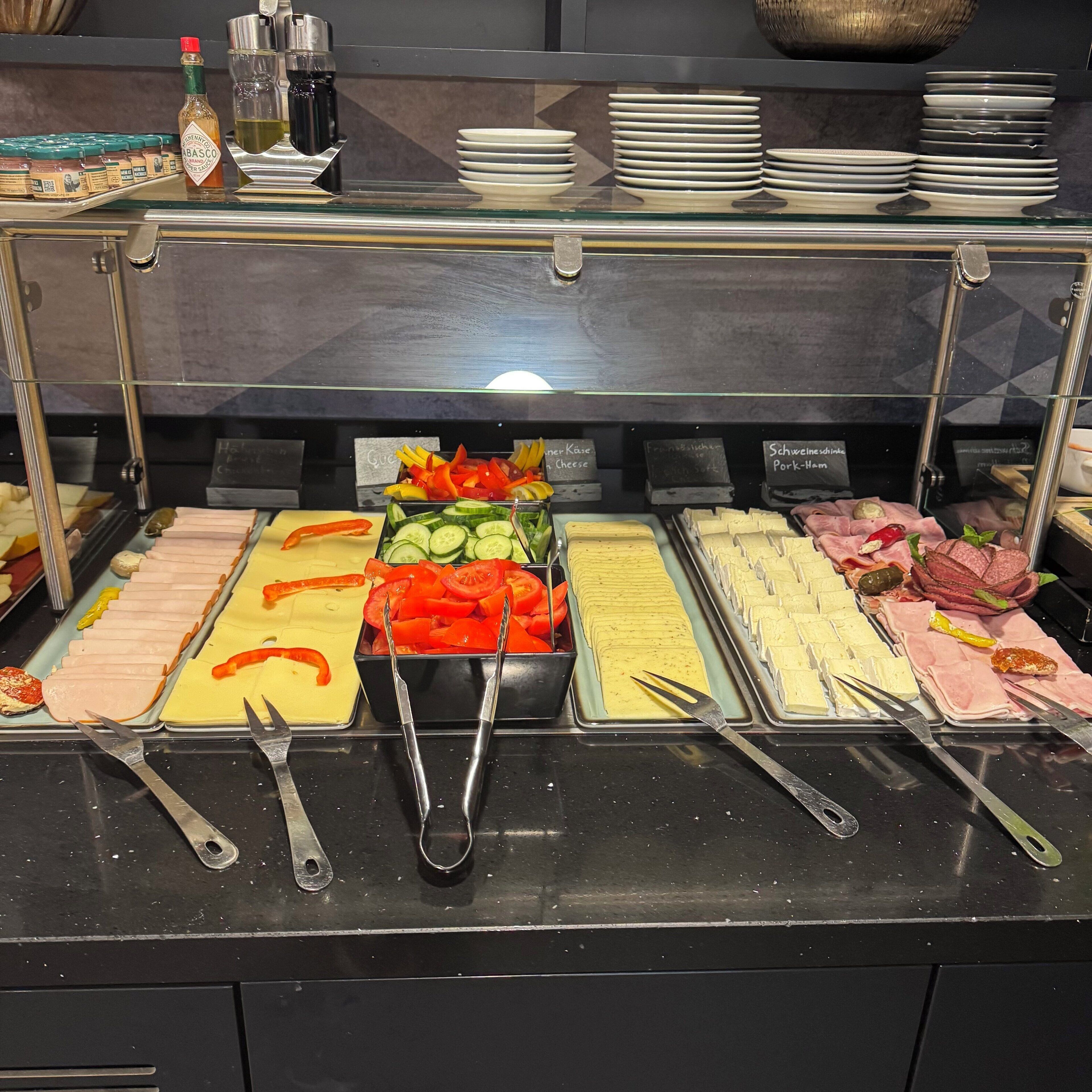 Ein Buffet mit verschiedenen Speisen, darunter Fleisch, Käse und Gemüse.