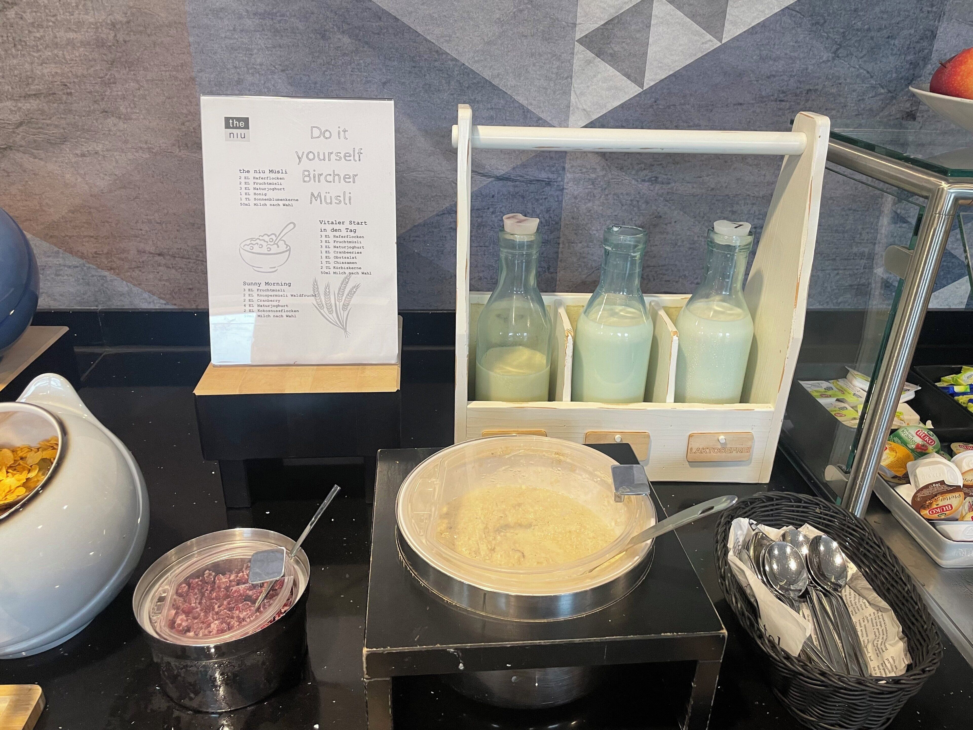 Ein Bereich für das Frühstücksbuffet mit einer Speisekarte, einem Milchspender und verschiedenen Speisen.