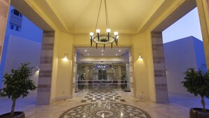 Un vestíbulo de hotel con suelo de cuadros, una lámpara de araña y plantas en macetas.