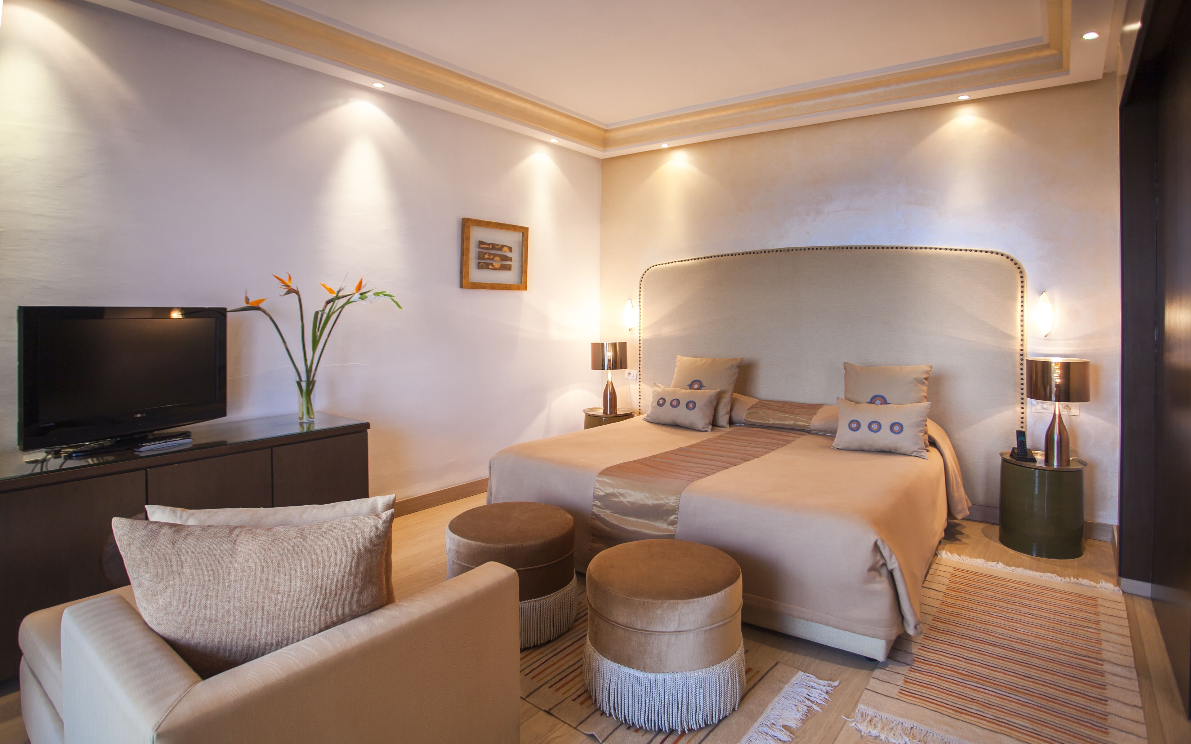 A hotel room with a large bed, a TV, a desk, and a chair.