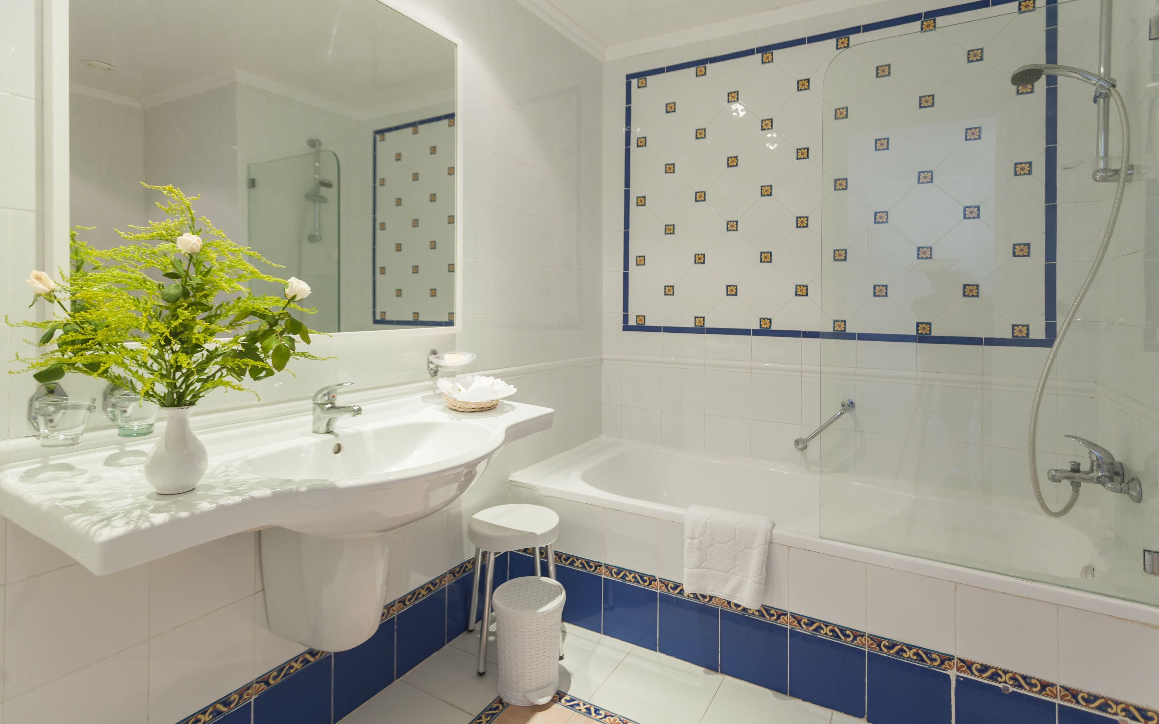 Un baño con lavamanos blanco, espejo, bañera y ducha.