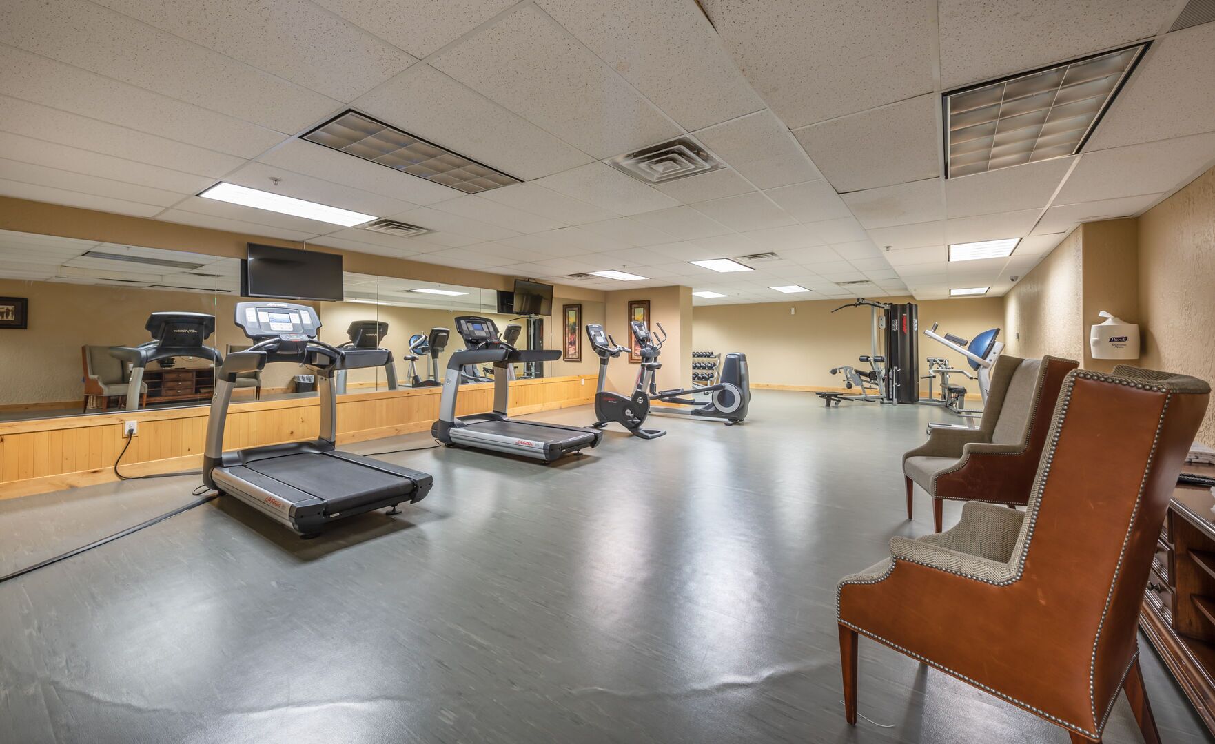 Une salle de sport équipée de tapis de course, de vélos d’appartement et d’un banc de musculation.