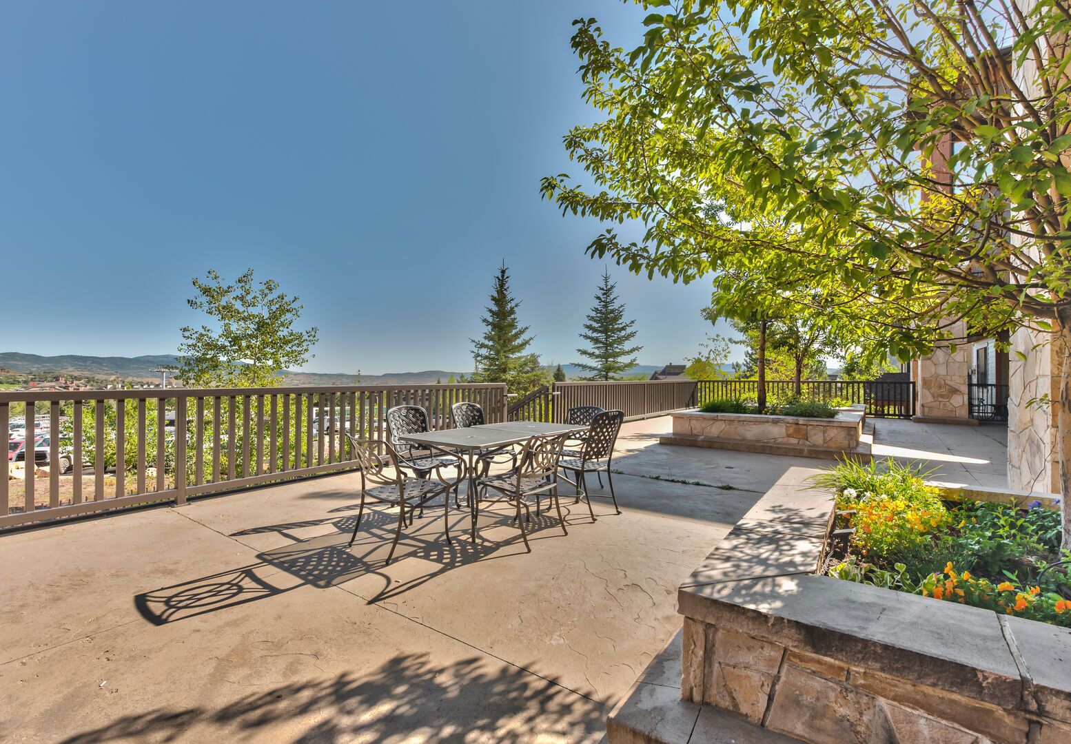 An outdoor patio with a table and chairs, surrounded by stone walls and greenery.