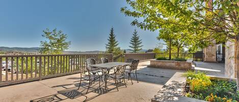 An outdoor patio with a table and chairs, surrounded by stone walls and greenery.