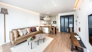A modern living room with a sofa, coffee table, and a dining area with a bench. - The Aewol House (Jeju City)