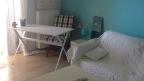 Un salon avec un canapé blanc, une table blanche et une lampe suspendue.