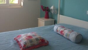 Une chambre à coucher comprenant un lit, une table de chevet, une fenêtre et une lampe fixée au mur.